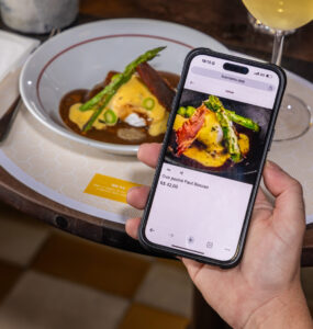 Mão segura celular com foto que ajuda a posicionar restaurante no Google