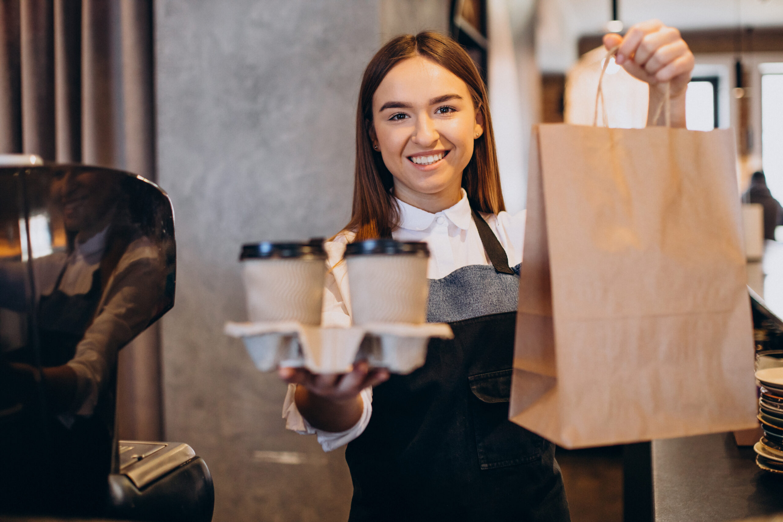 Mulher barista em uma cafeteria preparando café em copos de papelão ensina como aumentar as vendas de restaurante