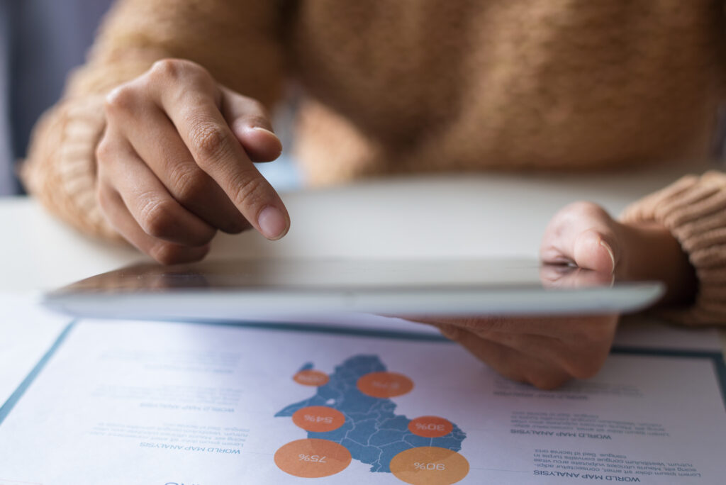Pessoa analisando dados em tablet sobre pesquisa de satisfação restaurante, avaliando indicadores e resultados de desempenho do atendimento e experiência dos clientes.