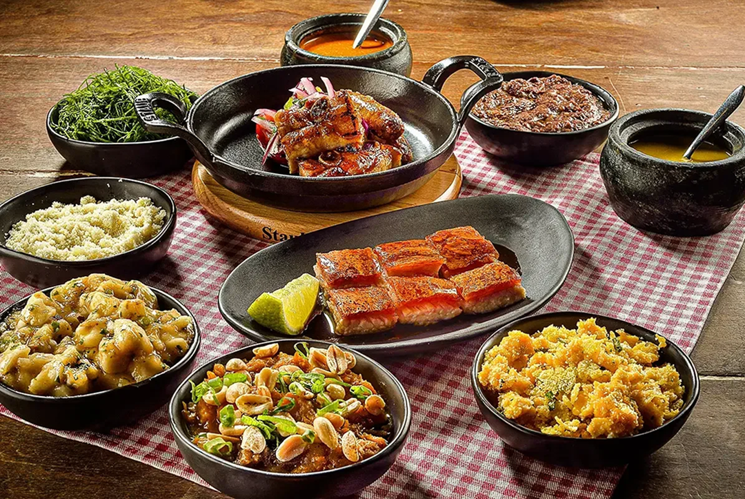 Pratos típicos servidos no restaurante A Casa do Porco, com destaque para carnes suínas e acompanhamentos tradicionais, dispostos sobre toalha xadrez.