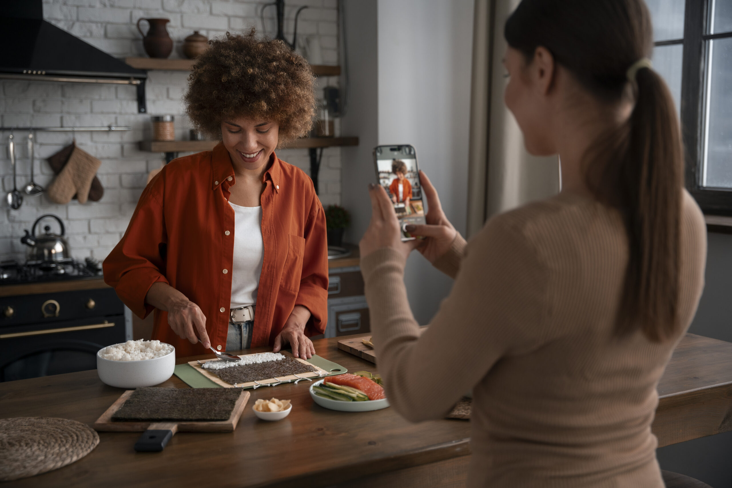Mulher grava preparo de sushi em cozinha, criando storytelling para restaurante com conteúdo autêntico e humano.
