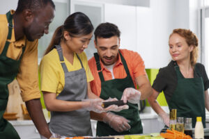 Equipe de restaurante preparando comida em conjunto, mostrando que a experiência do cliente começa na organização e colaboração nos bastidores.