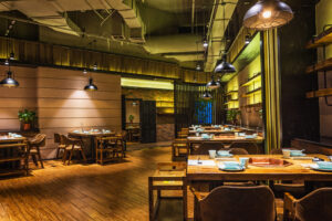 Interior de restaurante moderno com mesas organizadas e ambiente aconchegante, representando estratégias de gestão para aumentar o RevPASH no restaurante.