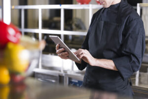 Chef com tablet na mão vendo dados para restaurante
