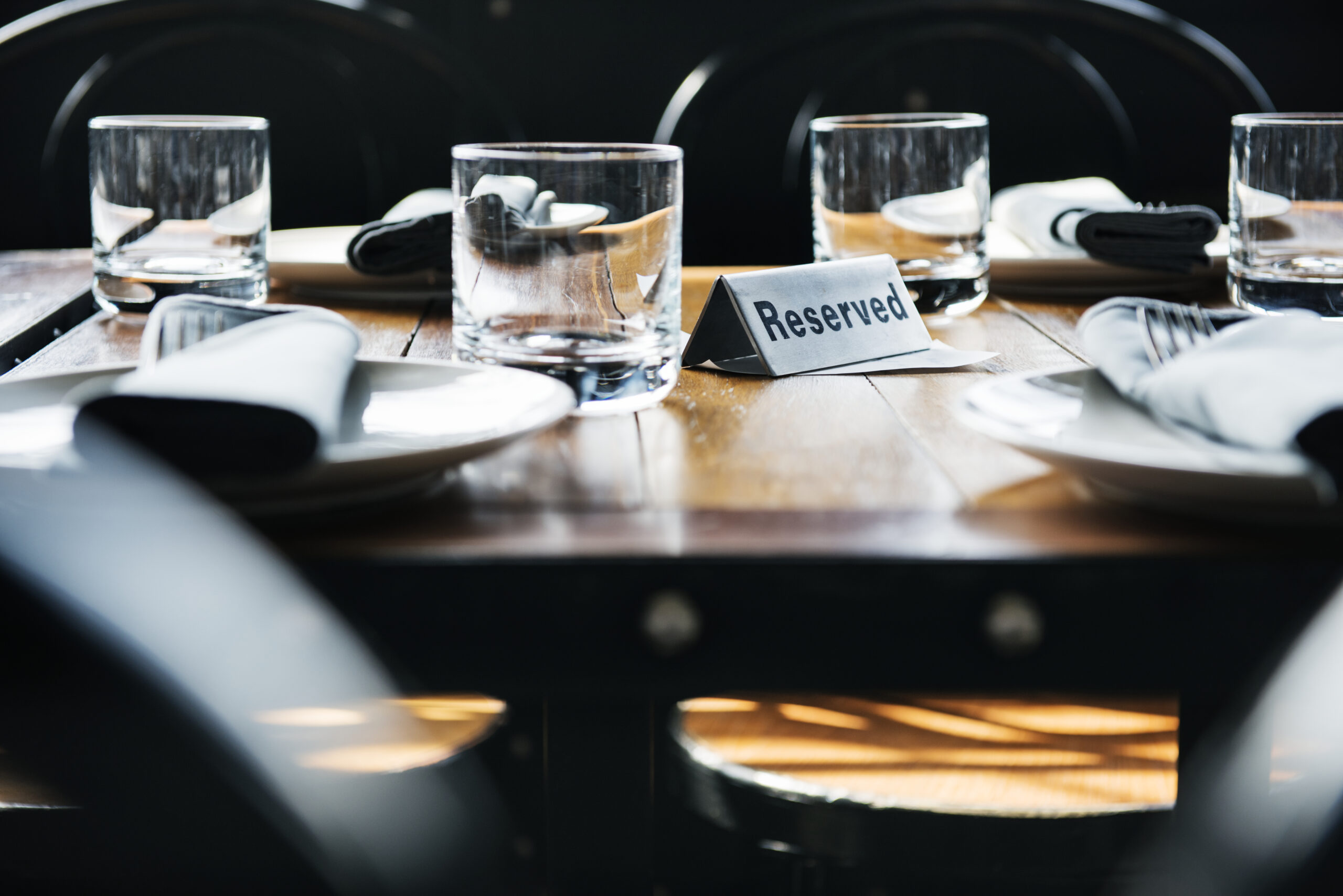Mesa de restaurante posta, vazia e passível de taxa de no-show, com ambiente elegante e luz suave ao entardecer