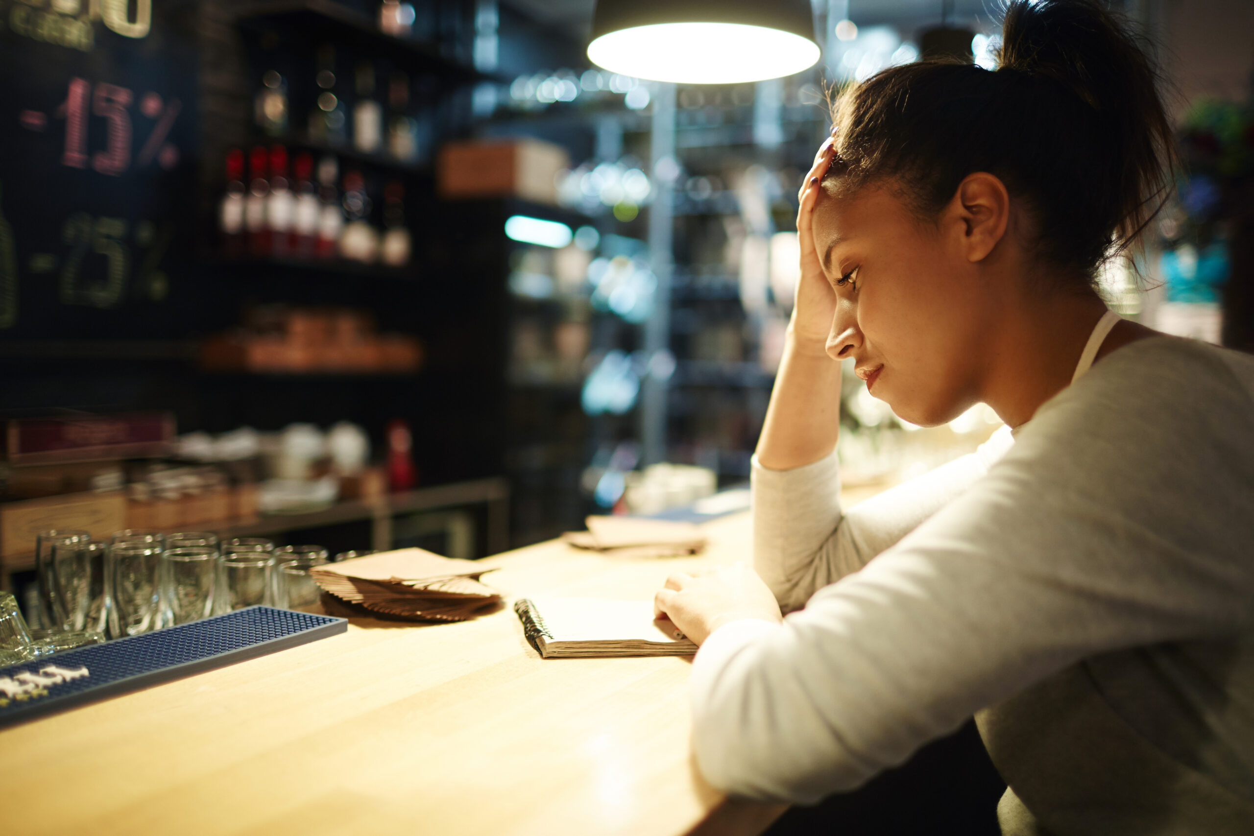 Empresária preocupada analisa o movimento vazio do restaurante, simbolizando os erros comuns em restaurantes que afetam a gestão e o faturamento.