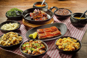 Pratos típicos servidos no restaurante A Casa do Porco, com destaque para carnes suínas e acompanhamentos tradicionais, dispostos sobre toalha xadrez.