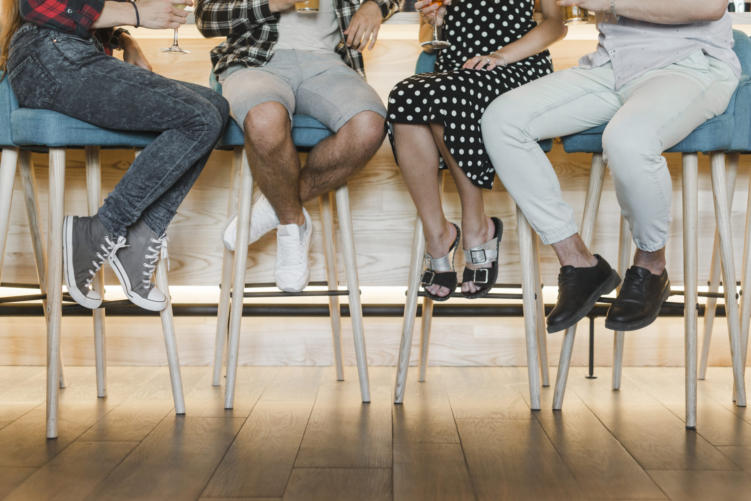Pessoas sentadas em bancos altos em um bar, segurando bebidas e conversando, ilustrando a gestão de lista de espera em ambientes gastronômicos movimentados.