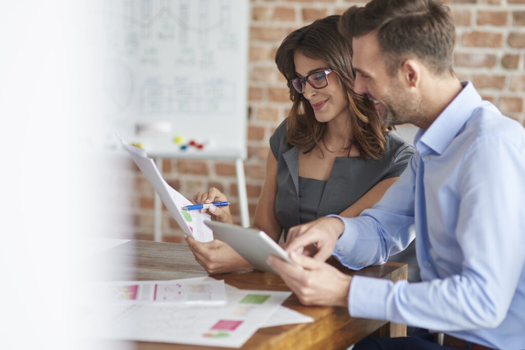 Duas pessoas em um escritório analisando o planejamento de marketing.