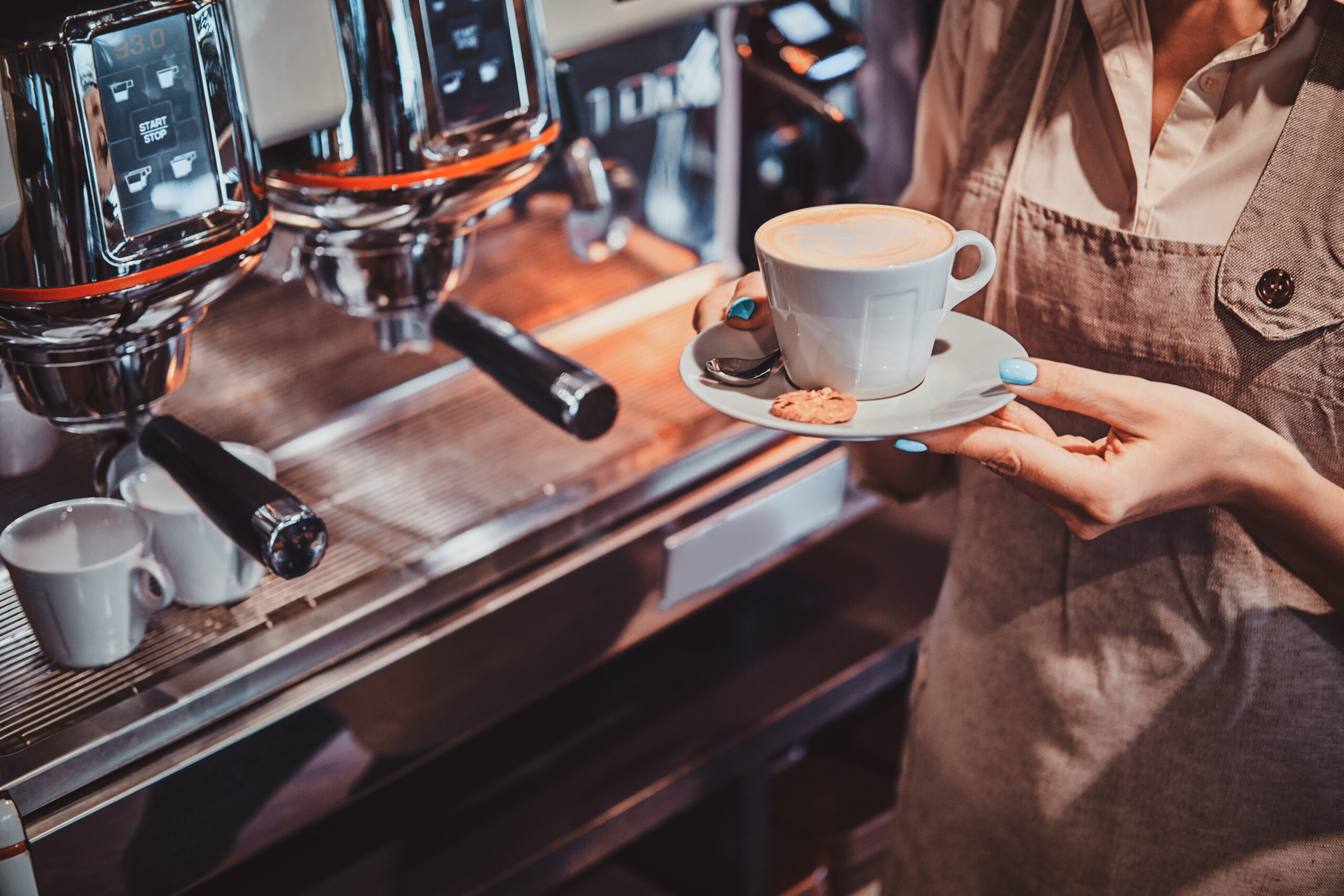 Barista preparando e servindo café expresso com latte art em máquina profissional, representando as tendências para cafeterias focadas em experiência, qualidade e apresentação do produto.
